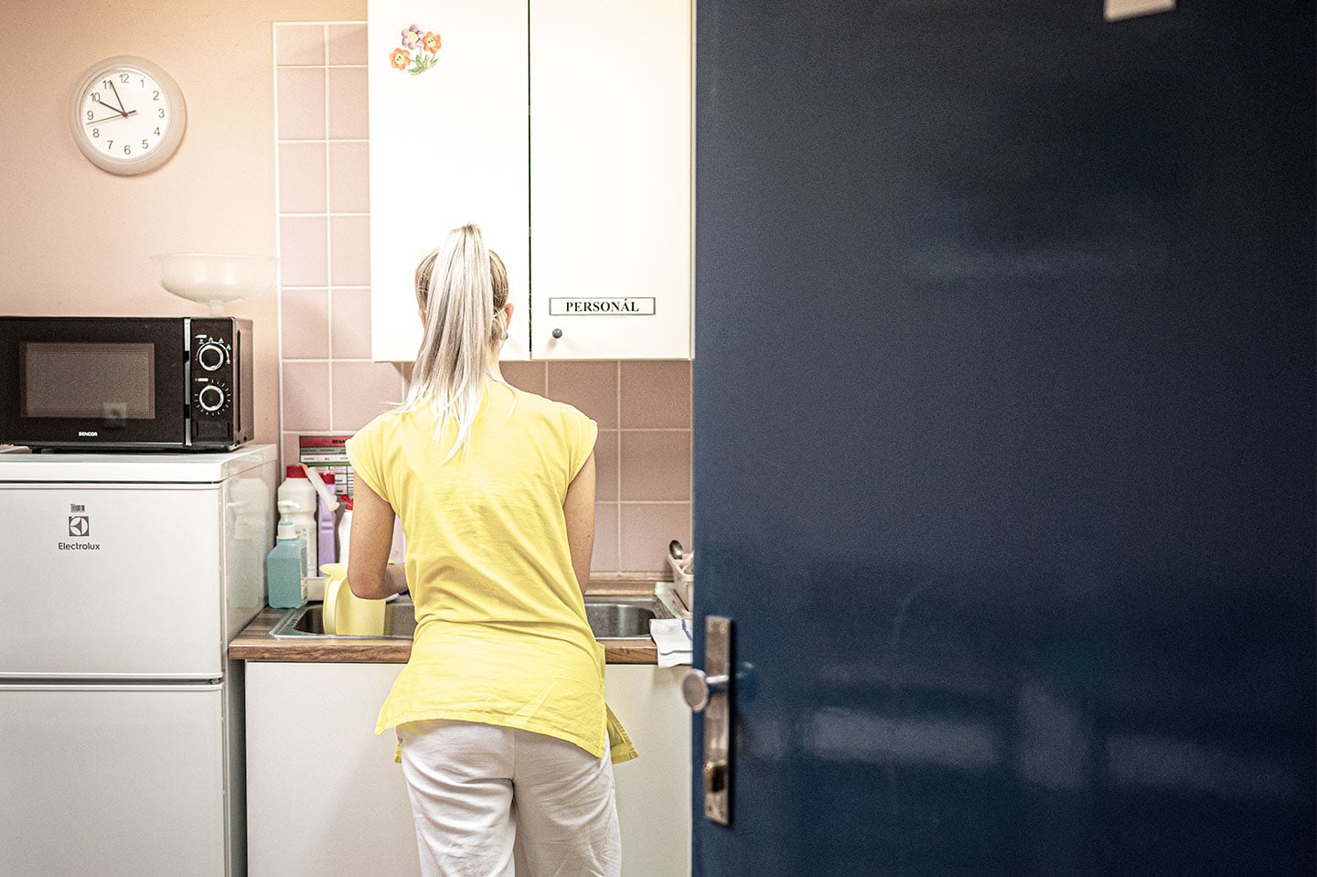 View into hospital kitchen with nurse disinfecting counters