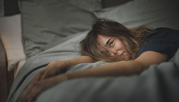 Dívka leží na posteli a připravuje se ke spánku v pravidelný čas