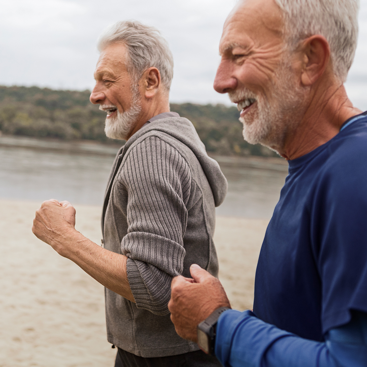 Zwei lächelnde ältere Männer joggen gemeinsam.