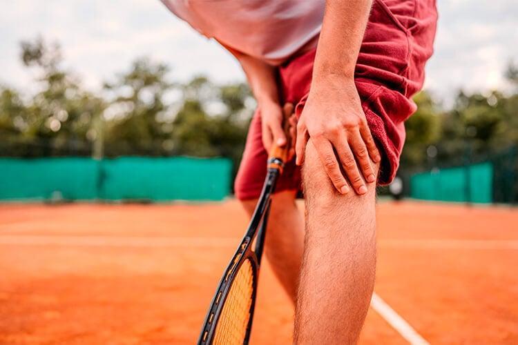 Hombre se toca la rodilla mientras juega a tenis