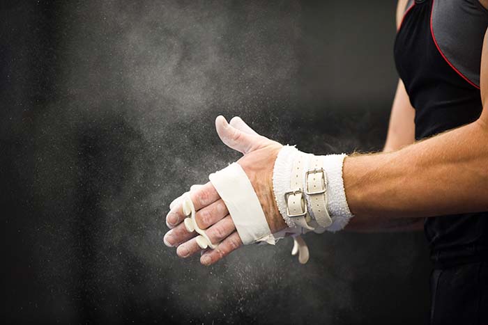 Atleta de gimnasia aplicando talco a las manos y al vendaje deportivo 