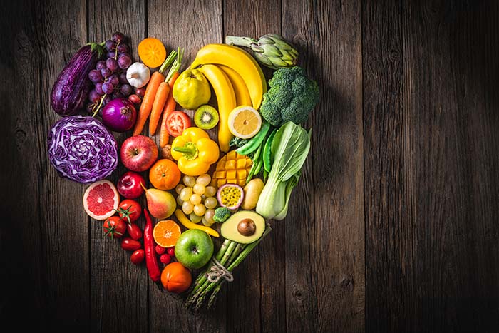 Mesa con frutas y verduras en dispuestas en forma de corazón para una buena salud cardiovascular